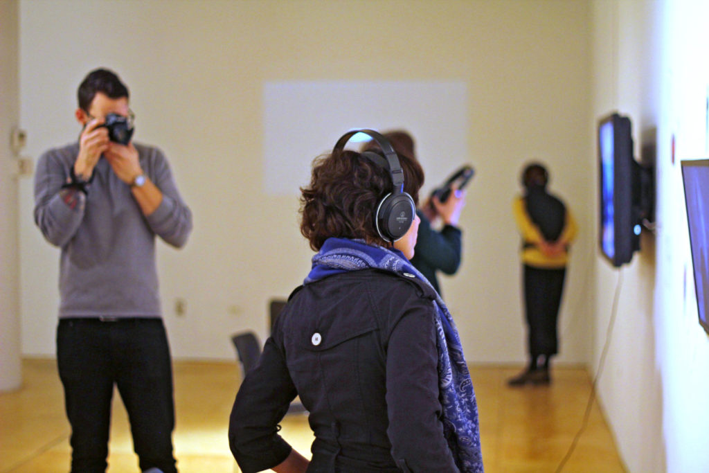 Art History woman being photographed by a man in a gallery.