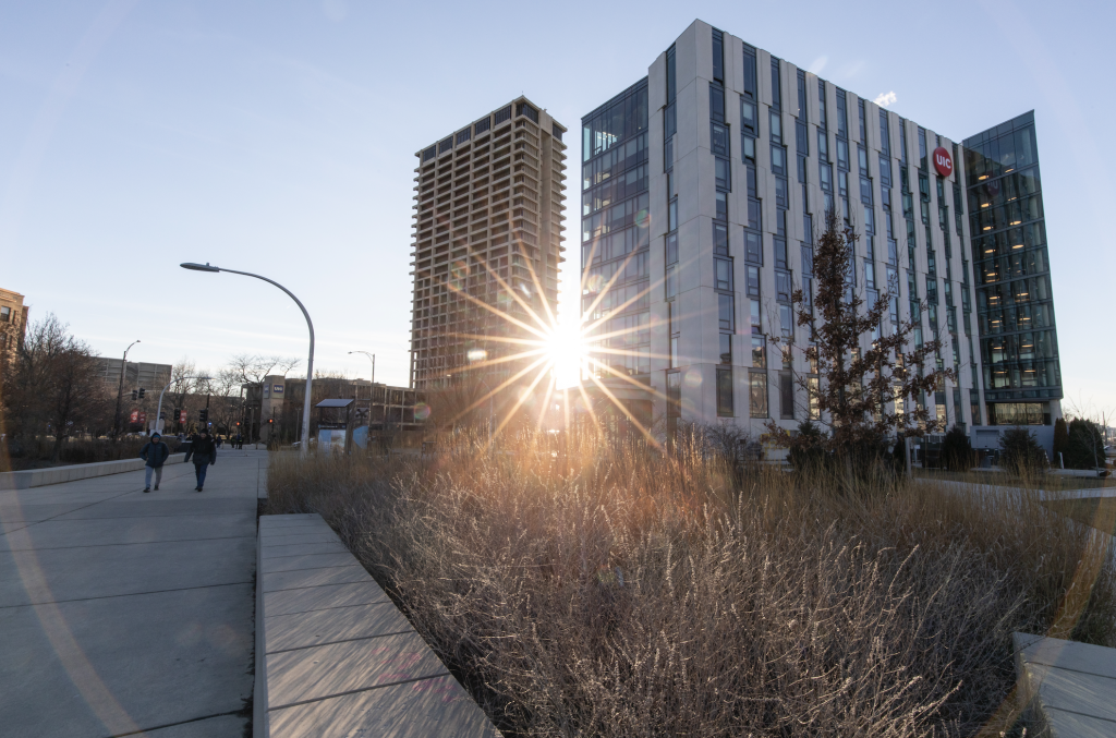 Image of sun setting between UIC University Hall and Academic and Residential Complex buildings on campus.